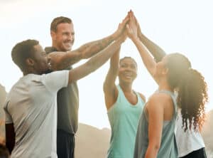 Shot of a group of friends high fiving one another before a workout.